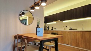 A modern kitchen with wooden cabinets, a dining table with chairs, and a mirror on the wall. - w* | Elegant 2BR w/ Balcony Near Larcomar (Miraflores)