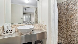 Un baño con un lavamanos blanco, un espejo y una pared de piedra.