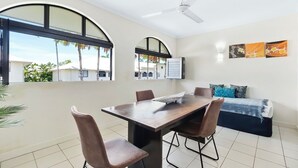 Una sala de estar moderna con una mesa de comedor, sillas, un sofá y un ventilador de techo.