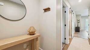 Ein Flur mit einem Holzkonsolentisch, einem Wandspiegel und einer kleinen Lampe.