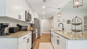 Eine moderne Küche mit weißen Schränken, Granit Arbeitsplatten, Edelstahlgeräten und einem eingebauten Backofen.