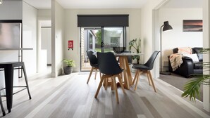 Una sala de estar moderna con un sofá negro, una mesa de centro y un comedor con una mesa y sillas negras.