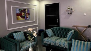 Ein Wohnzimmer mit zwei grünen Sofas, einem Couchtisch und einer Vase mit Blumen.