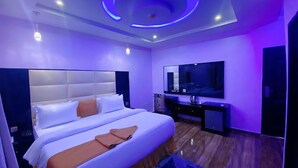 Ein modernes Schlafzimmer mit einem großen Bett, einem Flachbildfernseher und einer Decke mit runder Beleuchtung.