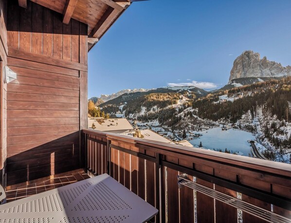 A wooden balcony with a view of a mountainous landscape and a lake. - Hotiday Apartments Santa Cristina (Santa Cristina Val Gardena)