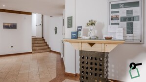 Zona de recepción con un mostrador, un cartel de bienvenida enmarcado y un tablón de anuncios con información.