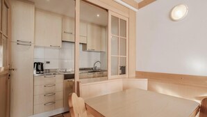 Una cocina moderna con armarios de madera, horno empotrado y comedor con mesa y sillas.