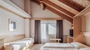 Una habitación de hotel con techo de madera, dos camas, una mesita y un televisor.