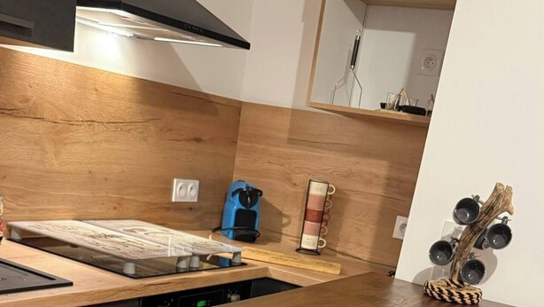 Eine Küche mit einem Holztisch, Stühlen und einer Kaffeemaschine.