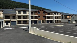 Eine mehrstöckige Parkgarage mit flachem Dach, umgeben von Gebäuden mit Balkonen und Garagentoren.