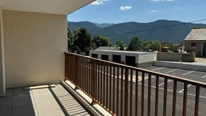 Ein Balkon mit Bergblick, ein Parkplatz und Baugeräte im Hintergrund.