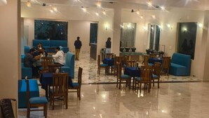 A spacious hotel lobby with blue seating areas, marble flooring, and pendant lighting.
