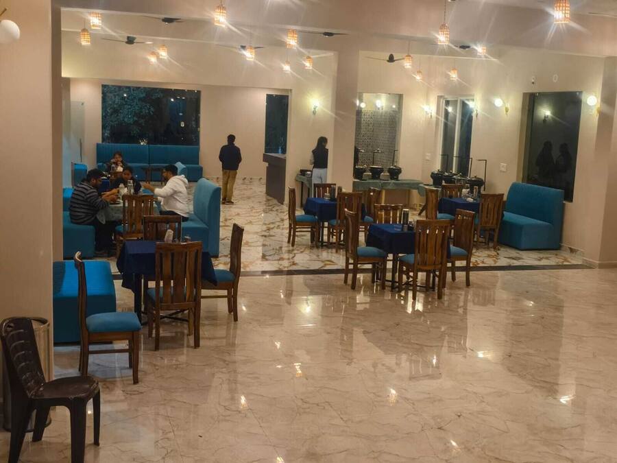 Un amplio hall de hotel con zonas de estar azules, suelo de mármol e iluminación colgante.