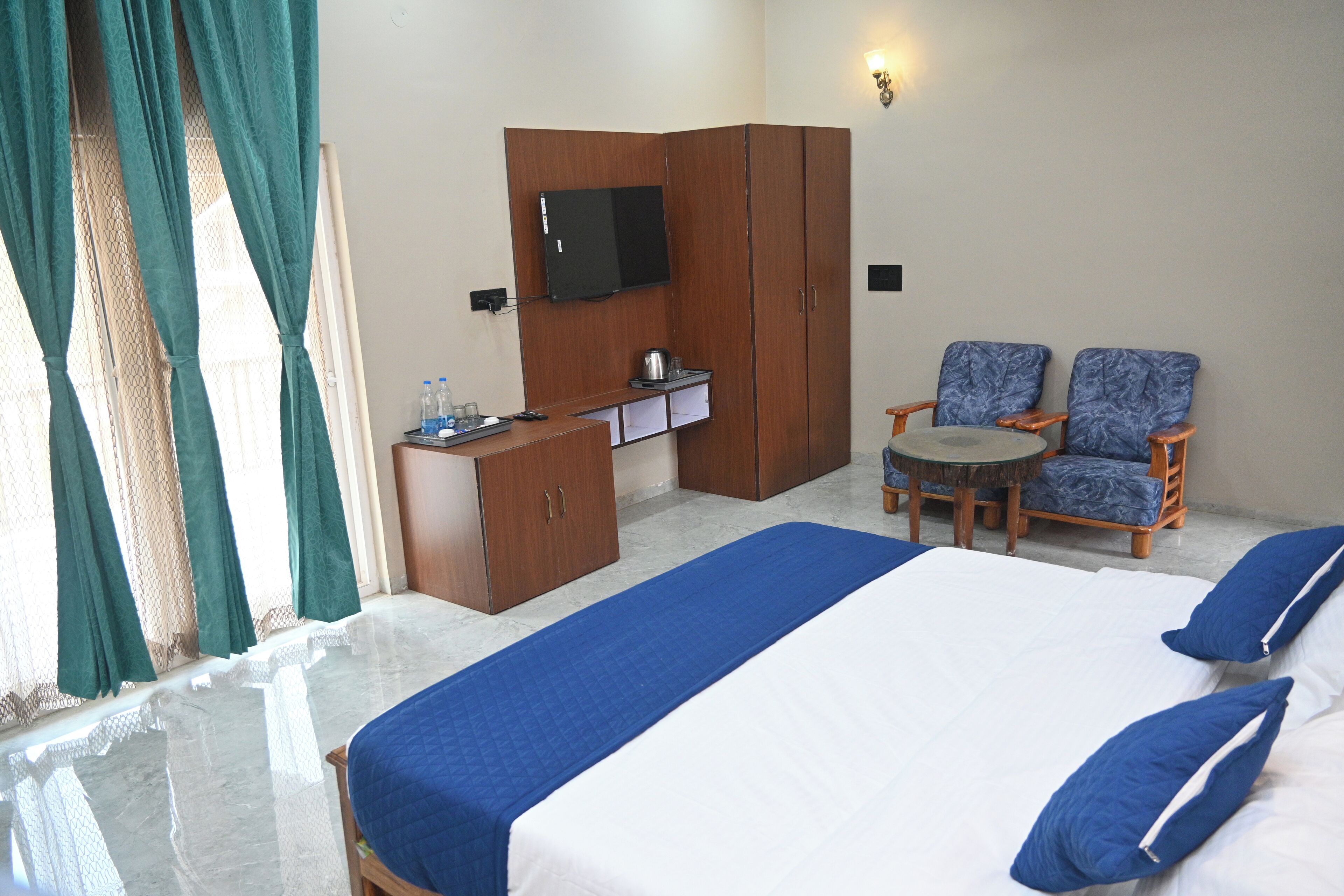 A hotel room with a bed, a desk, a chair, a television, and a small table.
