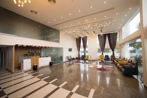A spacious lobby with a reception desk, seating area, and large windows. - Hotel Visakka - Palani (Palani)