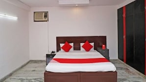 A bedroom with a bed, a ceiling fan, an air conditioning unit, and a red door. - Gurugram Home Residency (Gurugram)