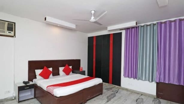 A bedroom with a bed, nightstand, and a ceiling fan. - Gurugram Home Residency (Gurugram)