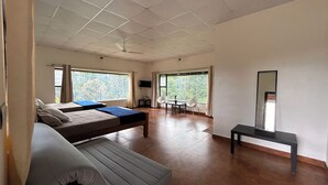Une chambre moderne avec deux lits, un bureau et une chaise. De grandes fenêtres offrent une vue sur l’extérieur.