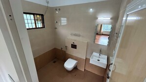 Une petite salle de bain compacte, équipée de toilettes, d’un lavabo et d’une douche.