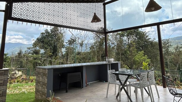 Une terrasse extérieure avec une table et des chaises, un luminaire suspendu et une vue sur le paysage environnant.