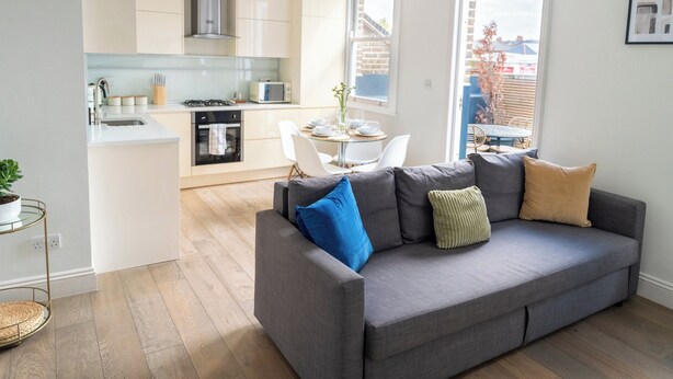 A modern living room with a grey sofa, a dining table with chairs, and a kitchen in the background. - Brixton/2bed Flat/privateterrace/tv/wifi (London)