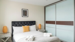 A modern hotel room with a large bed, a bedside table with a lamp, and a sliding glass door. - Brixton/2bed Flat/privateterrace/tv/wifi (London)