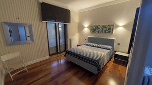 A bedroom with a bed, a chair, a radiator, a window with blinds, and a painting on the wall. - Comfortable stay in city center, stores, pedestrian island restaurants and bars. (Avellino)