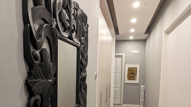 A hallway with a wooden floor, a decorative black mirror, and a framed picture on the wall. - Comfortable stay in city center, stores, pedestrian island restaurants and bars. (Avellino)