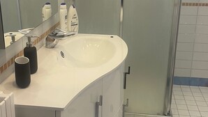 A bathroom with a white sink, a mirror, a glass shower enclosure, and a black rug. - Comfortable stay in city center, stores, pedestrian island restaurants and bars. (Avellino)