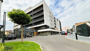Un edificio moderno de varios pisos con entrada cubierta y zona de estacionamiento.