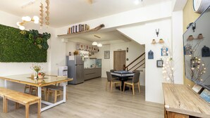 A modern kitchen with a built-in fridge, a dining area with a glass table, and a staircase leading to an upper level. - Turn Right Home (Wujie)