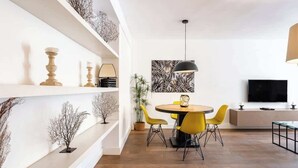 A modern dining area with a round table, yellow chairs, and a black pendant light.