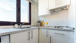 A modern kitchen with white cabinets, a window, a sink, and a dishwasher. - Unique Charming Apartment in the Heart of Málaga (Málaga)