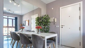 A modern dining area with a white table, grey upholstered chairs, and a large mirror on the wall. - Unique Charming Apartment in the Heart of Málaga (Málaga)