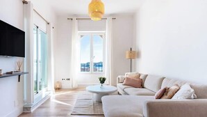 A modern living room with a sofa, a coffee table, and a TV mounted on the wall.