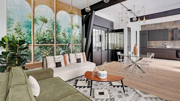Un salon moderne doté d’une grande fenêtre, d’un canapé, d’une table basse et d’un coin repas avec des chaises.