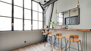 Une cuisine moderne dotée d’une grande fenêtre, de tabourets de bar et d’un comptoir en bois.