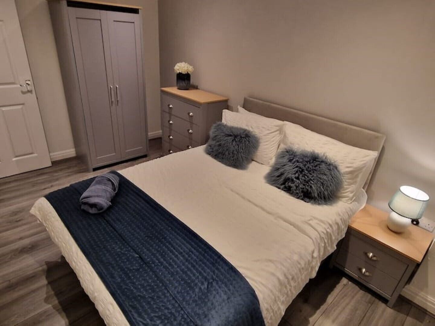 A bedroom with a bed, a nightstand, a dresser, and a wardrobe.