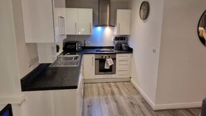 Een moderne keuken met witte kasten, een roestvrijstalen afzuigkap en een inbouwoven.