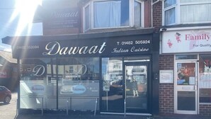 Een restaurant genaamd 'Dawaat' met een glazen gevel en een bord waarop 'Indische Keuken' staat.