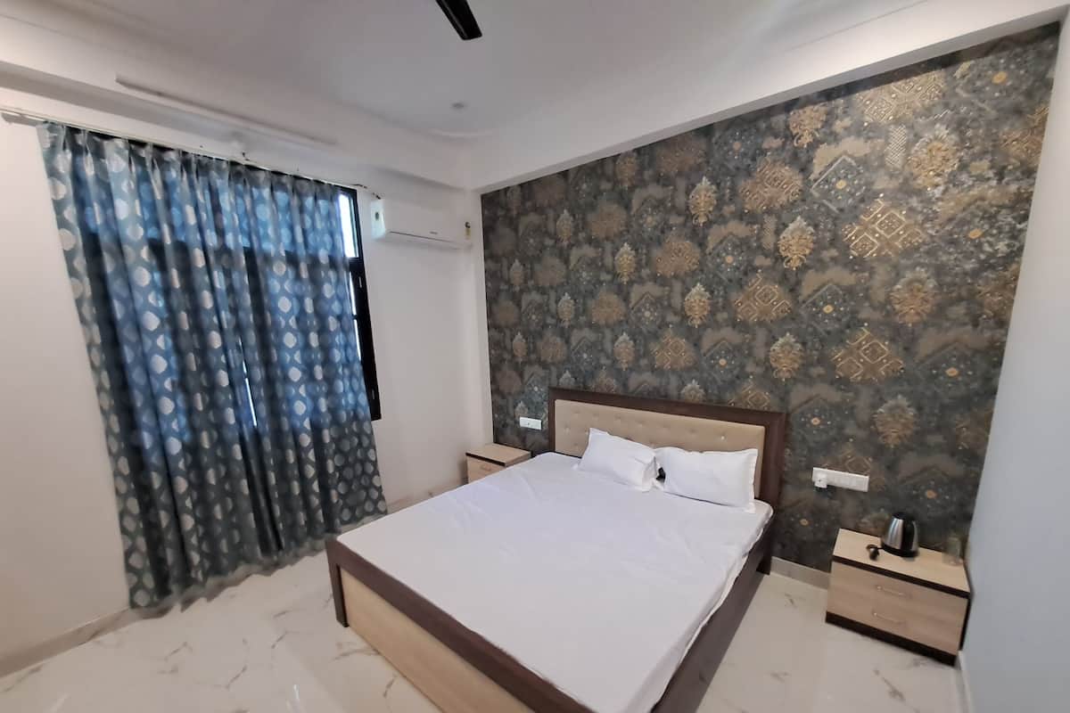 A bedroom with a bed, nightstands, a window with curtains, and a patterned wall.