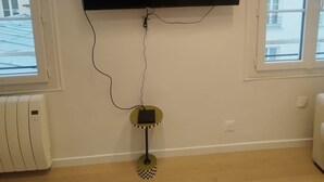 A room with a mounted TV on the wall, a radiator, and a window with a view of buildings. - Bail Mobilité - New Renovated Studio Invalides EiffelTower Paris 7 (Paris)