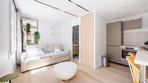 A modern living room with a sofa, a round coffee table, and a dining area with a table and chairs. - Bail Mobilité - New Renovated Studio Invalides EiffelTower Paris 7 (Paris)