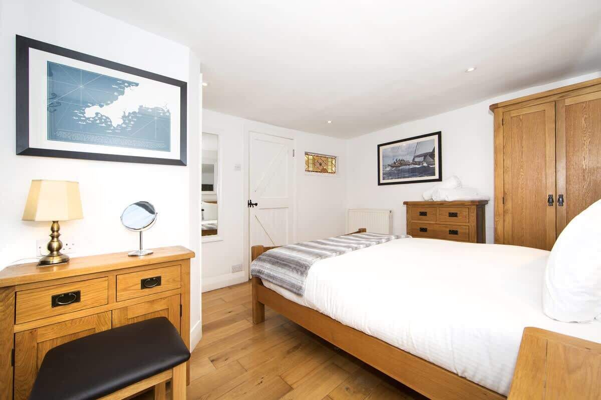 Un dormitorio con una cama de madera, una mesita de noche con lámpara, un aparador y un mapa enmarcado en la pared.