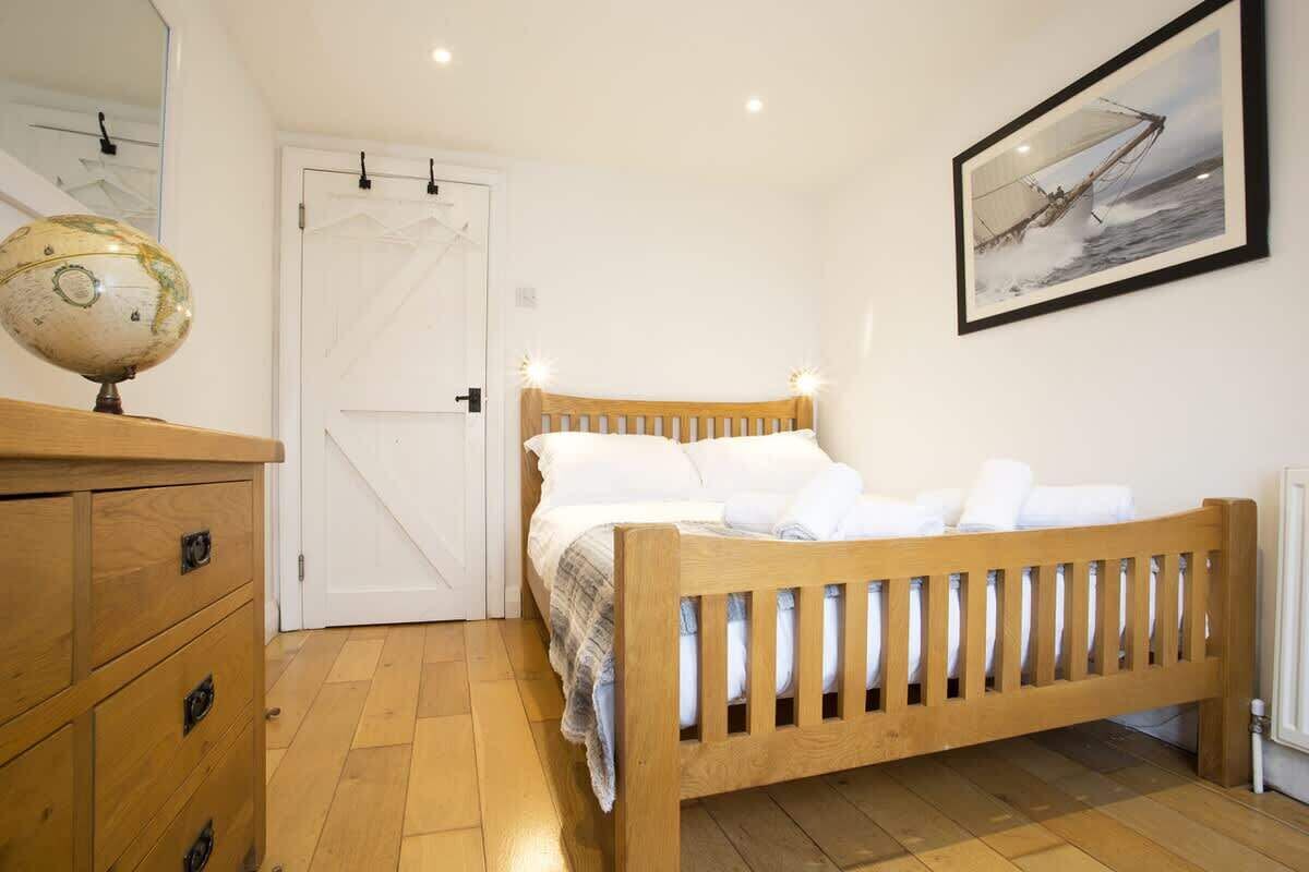 A bedroom with a wooden bed, a globe on a dresser, and a framed picture on the wall.