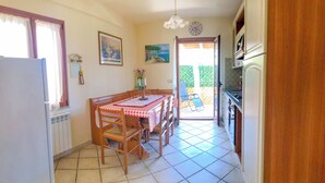 Una cocina con una mesa de comedor, sillas, un refrigerador y vistas al exterior.