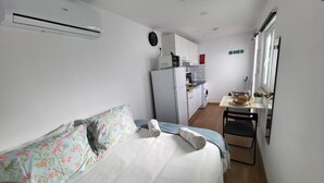 Une chambre compacte comprenant un lit, une petite kitchenette et donnant sur l’extérieur.