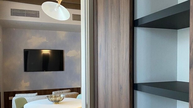 Un espace repas moderne avec une table ronde, des chaises et un téléviseur fixé au mur.