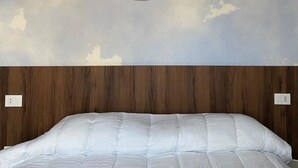 Une chambre à coucher avec un lit, une tête de lit en bois et un mur orné d’un motif circulaire.
