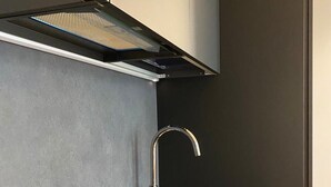 Une cuisine moderne dotée d’une plaque de cuisson intégrée, d’un évier en acier inoxydable et de meubles au design épuré.